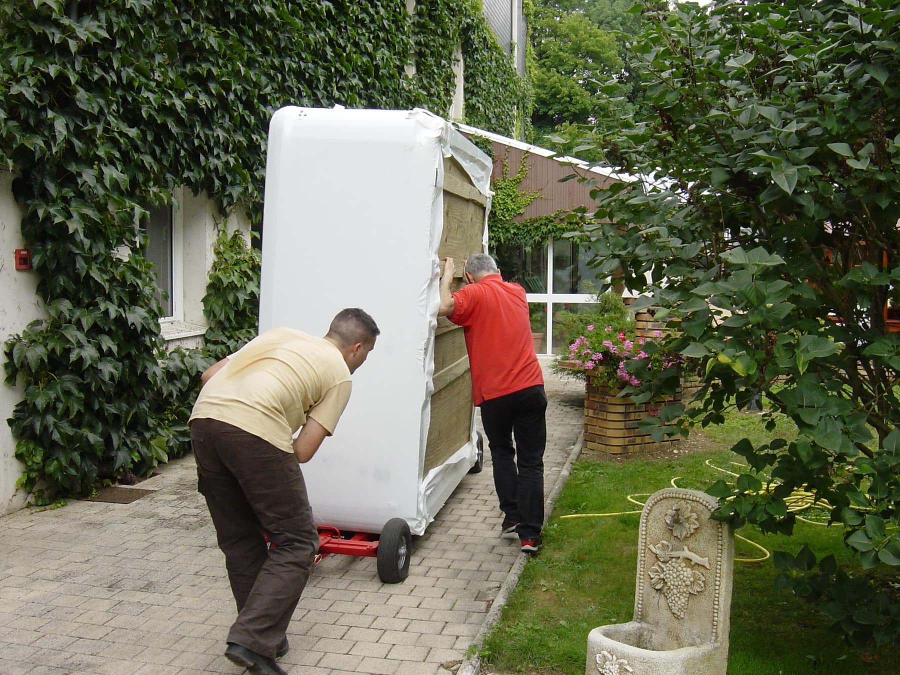 Deux techniciens EdenSpa déplaçant un spa sur un chariot de manutention